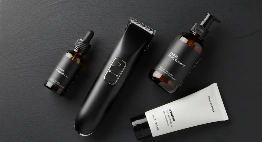 Premium all-in-one executive grooming kit featuring an electronic trimmer with ceramic blades, a glass bottle of hyaluronic facial cleanser, and lightweight beard oil on a minimalist dark stone surface.