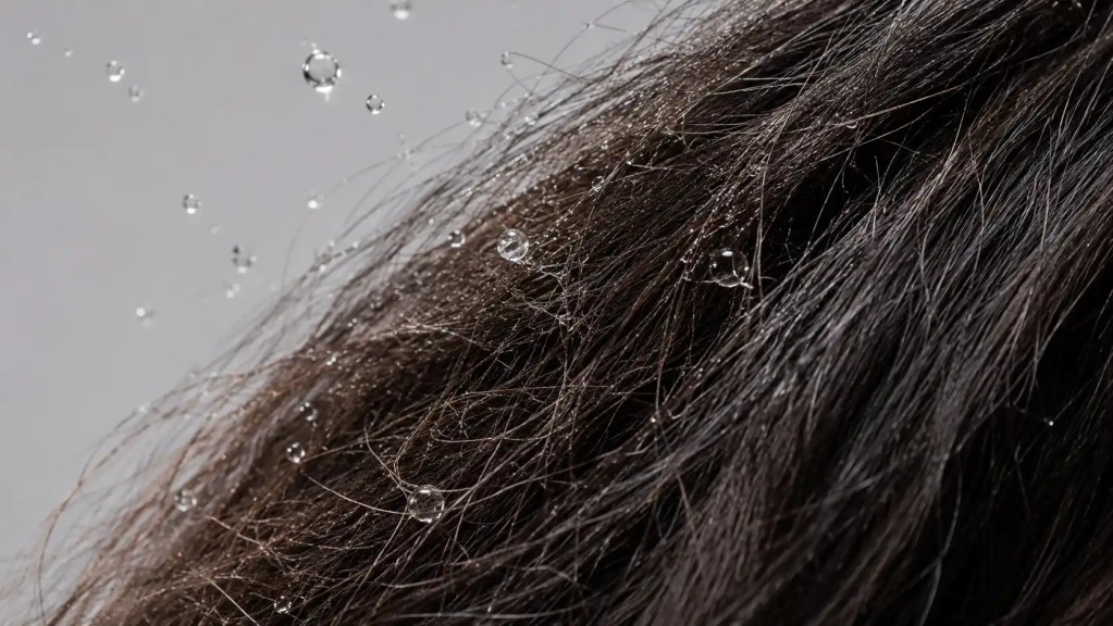 Microscopic comparison of a healthy clean hair strand versus a brittle strand coated in waxy hard water mineral buildup from borewell water.
