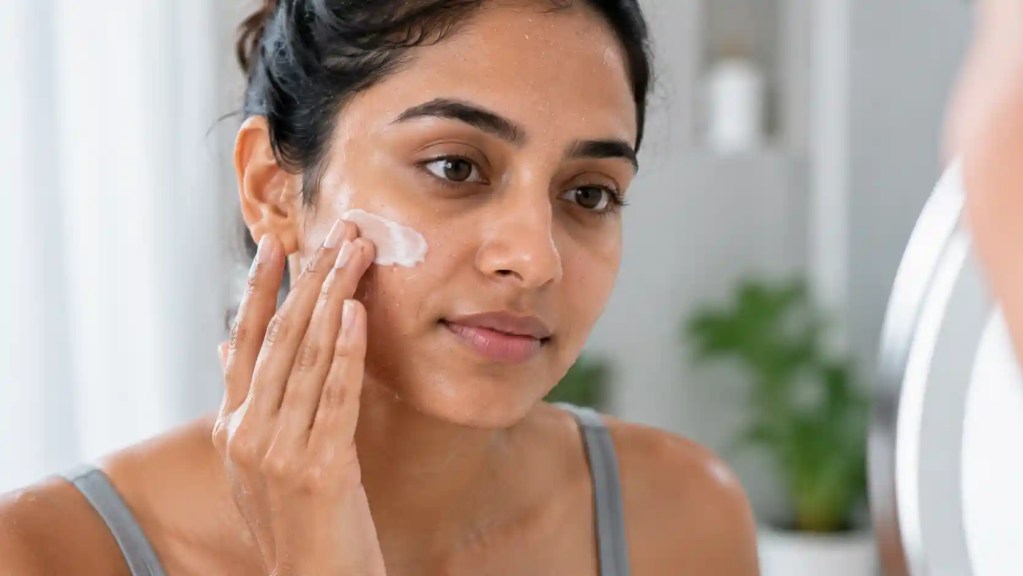 Indian woman applying a ceramide-rich moisturizer to damp skin after cleansing to help restore the skin barrier and lock in moisture.